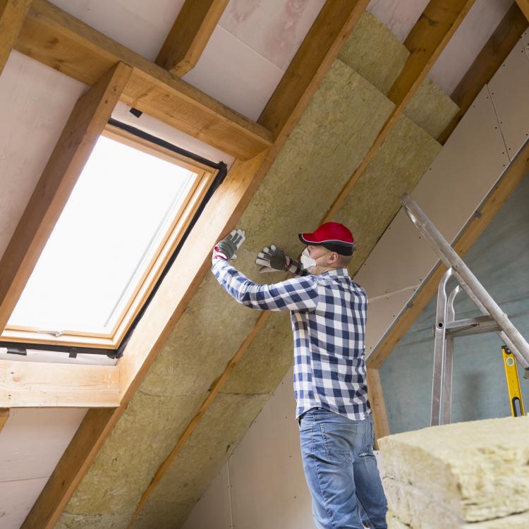 person putting insulation in a wall